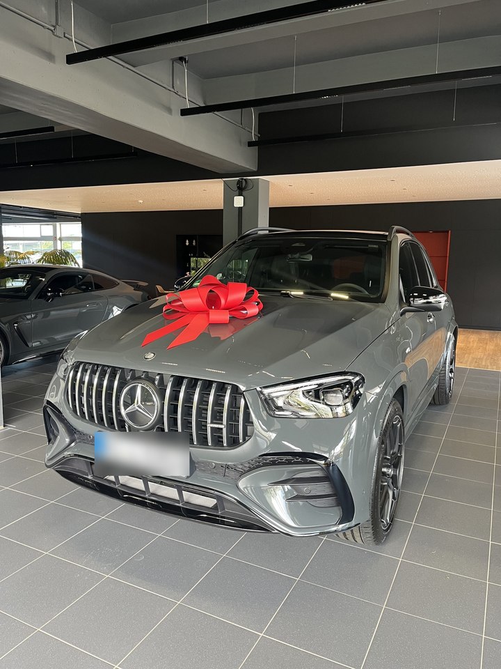 Mercedes-AMG GLE mit roter Schleife bei der Fahrzeugübergabe im Ausstellungsraum